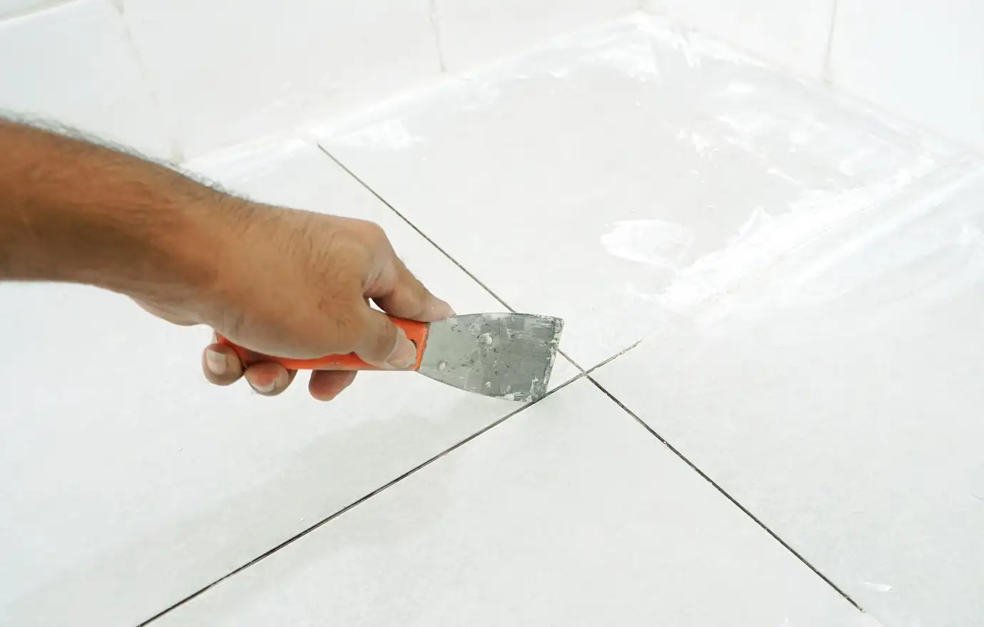 Man using trowel to remove old grout